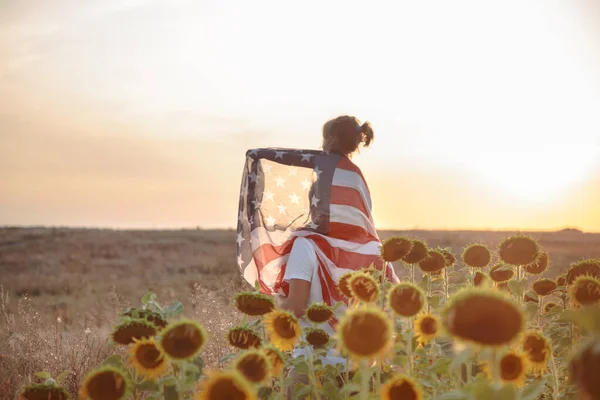 Eine glückliche Familie mit einer amerikanischen Flagge bei Sonnenuntergang. — Stockfoto