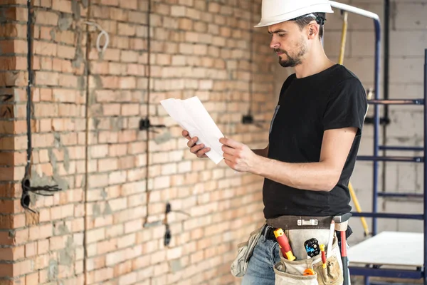 Builder handyman with construction tools, looking at the drawing — Stock Photo, Image