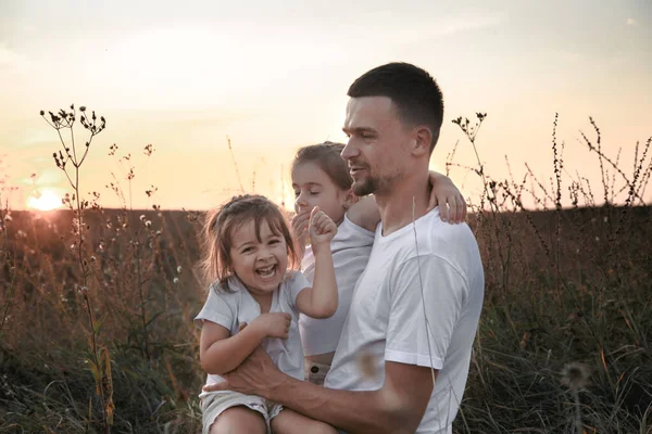 Папа и его дочери в поле на закате  . — стоковое фото