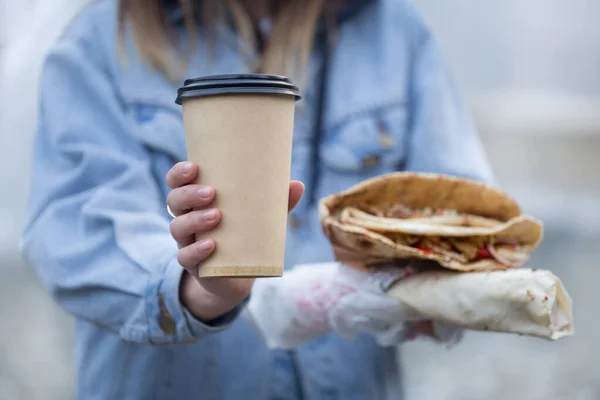 Una giovane donna con un bicchiere di caffè e fast food . — Foto Stock
