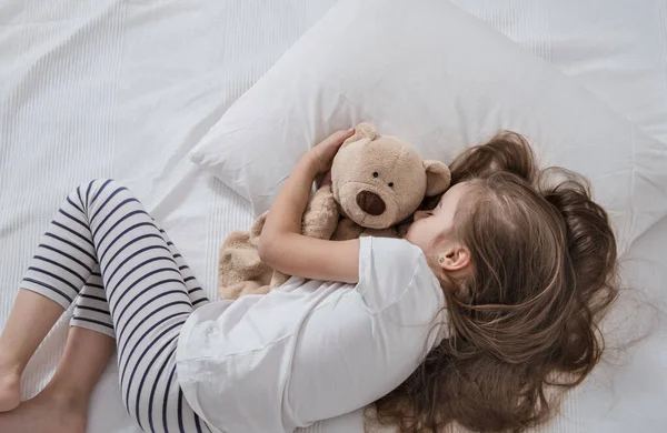 Niedliches kleines Mädchen im Bett mit Plüschtier. — Stockfoto