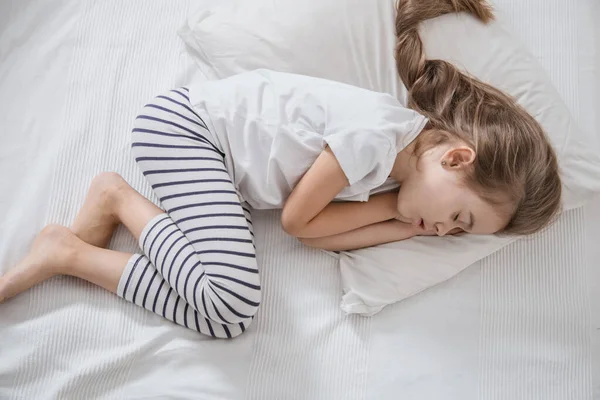 Süßes kleines Mädchen mit langen Haaren schläft im Bett. — Stockfoto