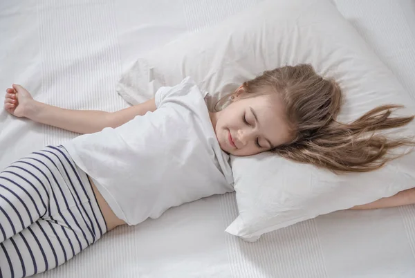 Linda niña con el pelo largo durmiendo en la cama . — Foto de Stock