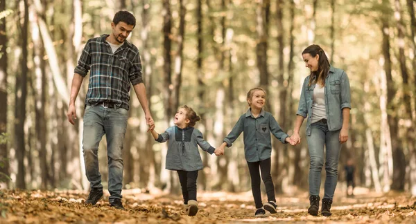 Una familia joven camina en el bosque de otoño con niños . — Foto de Stock
