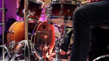 Stüdyoda davulcu var. Tekme davul pedalı çalıyor. Davul setinin arkasındaki müzisyen. Statik video kaydı.
