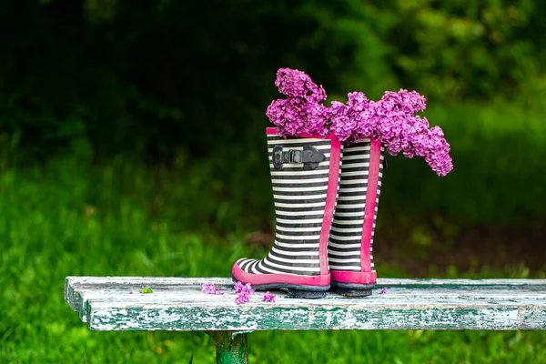 ライラックの花の花束とラバーブーツ 創造的なコンセプト — ストック写真