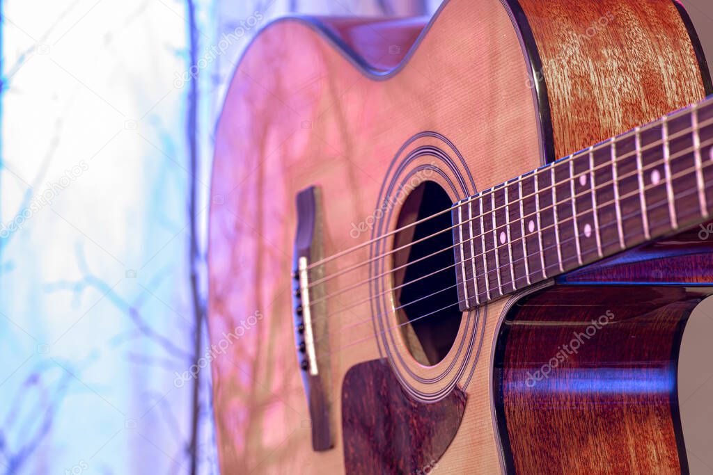 Acoustic guitar on a beautiful colored background. The concept of stringed instruments. Close up.