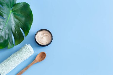 Renkli bir arka planda vücut bakım ürünleri olan bir spa kompozisyonu ve bir canavar yaprağı. Spa konsepti.