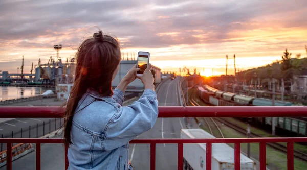 Młoda Kobieta Fotografuje Piękny Zachód Słońca Mostu Przez Telefon — Zdjęcie stockowe