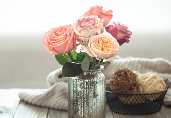 A cozy arrangement with roses in a vase on a wooden table .