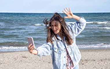 Genç ve şık bir kadın sahilde selfie çekiyor..