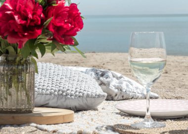Deniz kenarında çiçekler ve bir bardak şampanyayla piknik. Tatil kavramı..