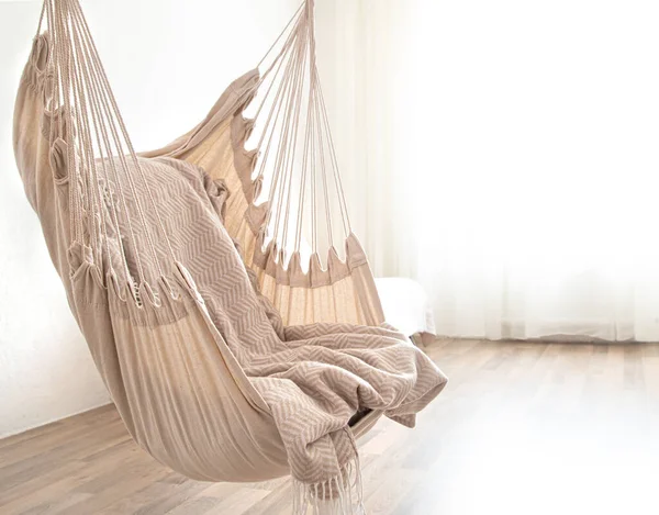 Hammock chair in boho style. Cozy interior. The concept of rest and home comfort. Space for text.