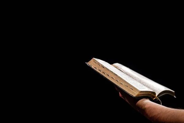 A man holds an open Bible. The concept of a relationship with God. Close up.