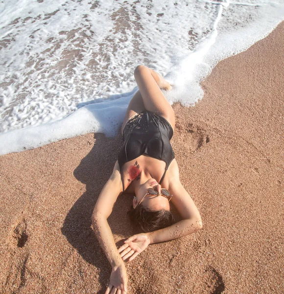 Όμορφη Γυναίκα Μαύρο Μαγιό Ξαπλωμένη Στην Άμμο Δίπλα Στη Θάλασσα — Φωτογραφία Αρχείου