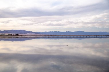 Gün batımında deniz kenarında güzel bir manzara. Uzakta yalnız figürlerle.