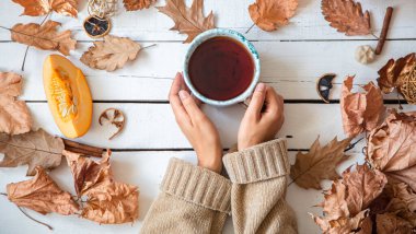 Yapraklı sonbahar kompozisyonu ve beyaz arka planda bir fincan çay. Sonbahar konsepti.