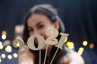 Yeni yıl 2021. Bir yüz kızının arka planındaki ahşap numaraya yakın plan.