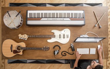 Akustik gitar, bas gitar, müzikal anahtarlar, kulaklıklar, ses karıştırıcı, davul ve bilgisayarın bir müzik stüdyosundaki kahverengi bir masada birleşimi.