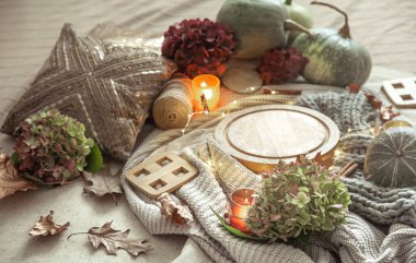 Balkabaklarının sonbahar kompozisyonu, ortanca çiçekleri, mumlarla süslenmiş ev dekorasyonu ve odanın bulanık arka planında bir gerdanlık..