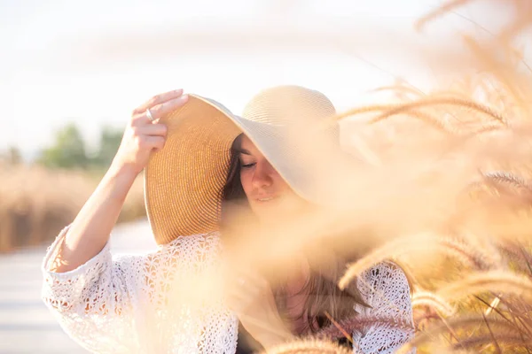 太陽の下で若い女性の肖像画 フィールドに座って 夏の服や帽子を着て — ストック写真