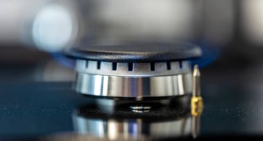 Paslanmaz çelik gövdeli, minimalist tarzda modern bir gaz ocağının makro çekimi. Yumuşak ışıklandırma çeliğin parlaklığını ve çağdaş hissi vurgular..