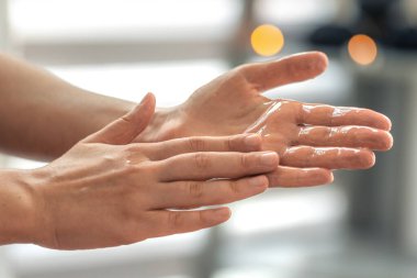 Yumuşak bokeh ışıkları olan parlak yağları tutan eller. Kişisel bakım ritüeli stili, saflığı ve sakinliği vurguluyor..