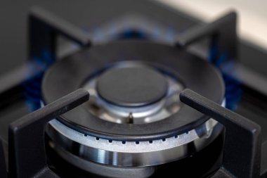 Temiz mavi alevi olan aktif bir gaz ocağının simetrik bileşimi. Makro detay, gösterişli hassasiyet ve yüksek teknoloji mutfak zarafeti..