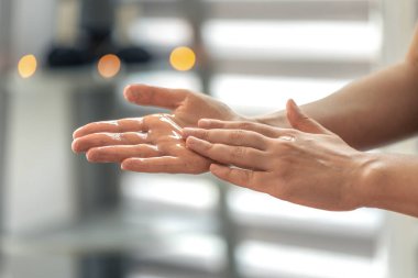 Hands spreading oil across the palm before massage in window light. Clean aesthetic with everyday self care and modern minimal style.