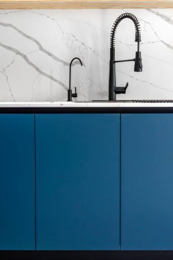 Siyah profesyonel bahar musluğu ve temiz bir minimalist mutfak görüntüsü için beyaz mermer kaplamalı matte mavi avuçsuz çift..