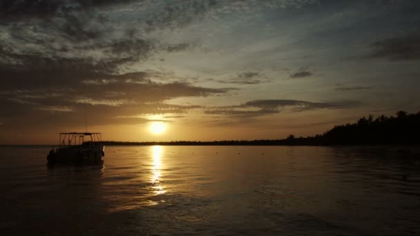 O barco balança nas ondas nos raios do pôr-do-sol — Vídeo de Stock