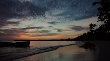 Tropikal ada plajı ve palmiye ağaçları üzerinde gün doğumu
