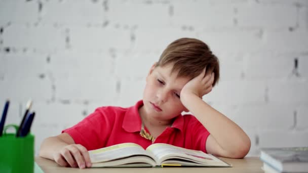Skolpojke trött på att läsa läroboken — Stockvideo