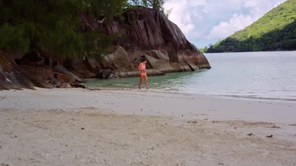 Gyönyörű fiatal lány sétál a tengerparton, a lagúna a Seychelle-szigetek. — Stock videók