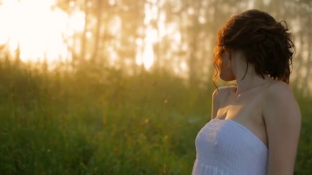 Belle fille dans une robe blanche dans la forêt d'été ensoleillée . Séquence Vidéo