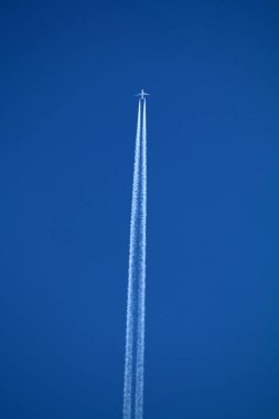 Gökyüzünde uçan uçak kimyasal izleri sol tarafta.