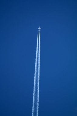 Gökyüzünde uçan uçak kimyasal izleri sol tarafta.