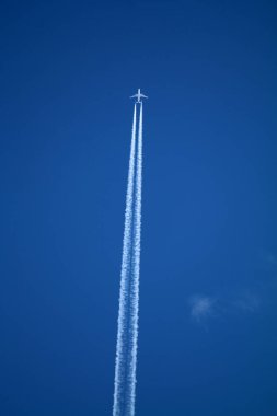 Gökyüzünde uçan uçak kimyasal izleri sol tarafta.