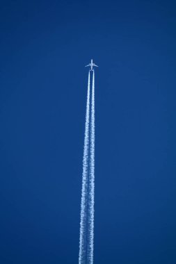 Gökyüzünde uçan uçak kimyasal izleri sol tarafta.
