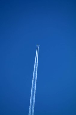 Gökyüzünde uçan uçak kimyasal izleri sol tarafta.