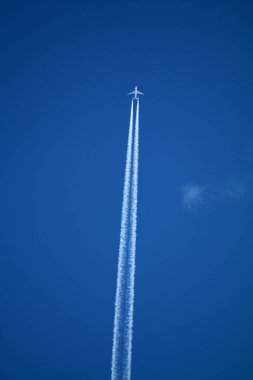 Gökyüzünde uçan uçak kimyasal izleri sol tarafta.