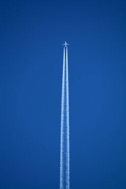 Gökyüzünde uçan uçak kimyasal izleri sol tarafta.