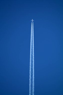 Gökyüzünde uçan uçak kimyasal izleri sol tarafta.