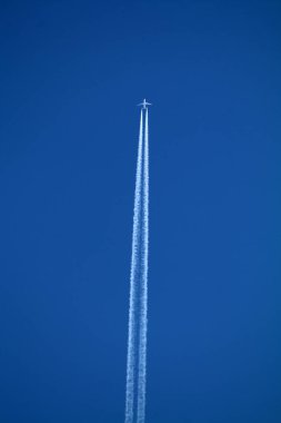 Gökyüzünde uçan uçak kimyasal izleri sol tarafta.