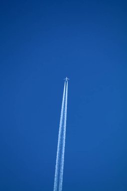 Gökyüzünde uçan uçak kimyasal izleri sol tarafta.