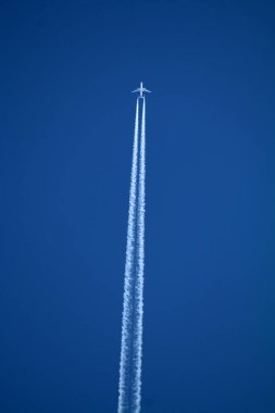 Gökyüzünde uçan uçak kimyasal izleri sol tarafta.