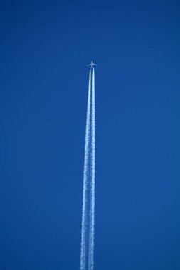 Gökyüzünde uçan uçak kimyasal izleri sol tarafta.