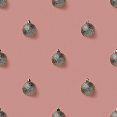 Pembe pastel arka planda gümüş renkli parlak Noel süsleri. Noel süsleri. Minimum bileşim, pürüzsüz kalıp arka plan. Noel ve Yeni Yıl konsepti. Üst manzara, düz uzanma