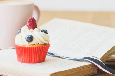 Kek Ahududu ve yaban mersini, fincan sıcak cappuccino, yumuşak odak arka plan ile