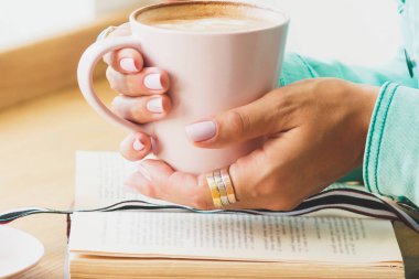 Kadın bir fincan kapuçino ellerini, yumuşak odak arka plan ile